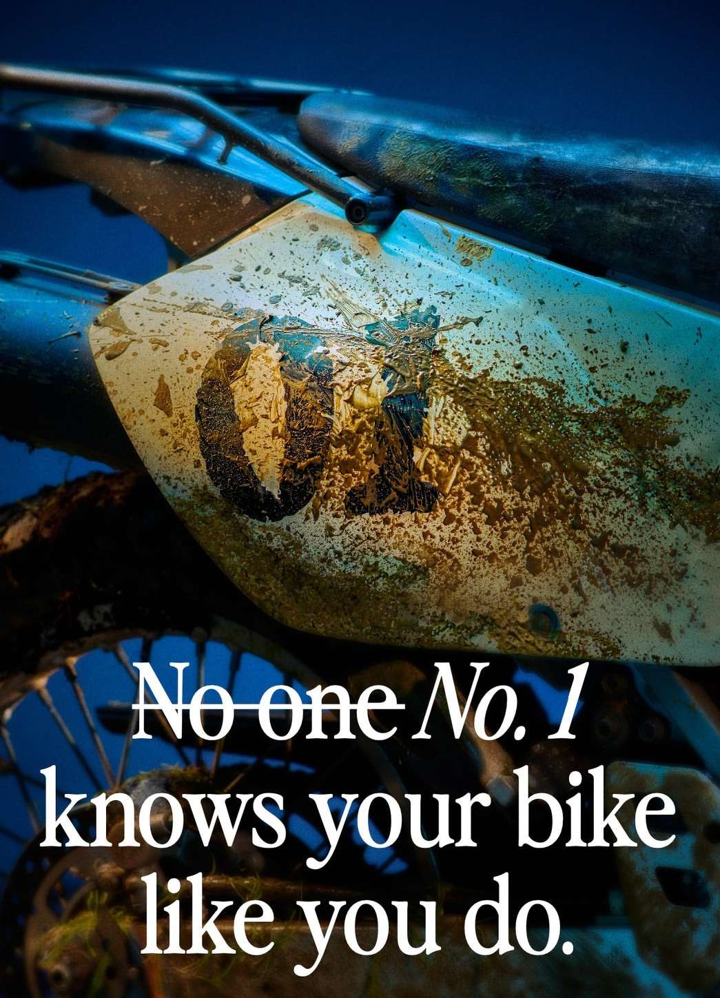 Closeup of the rear fender of a motocross bike with the number 01 displayed, covered in dirt and mud splatters, against a dark background.